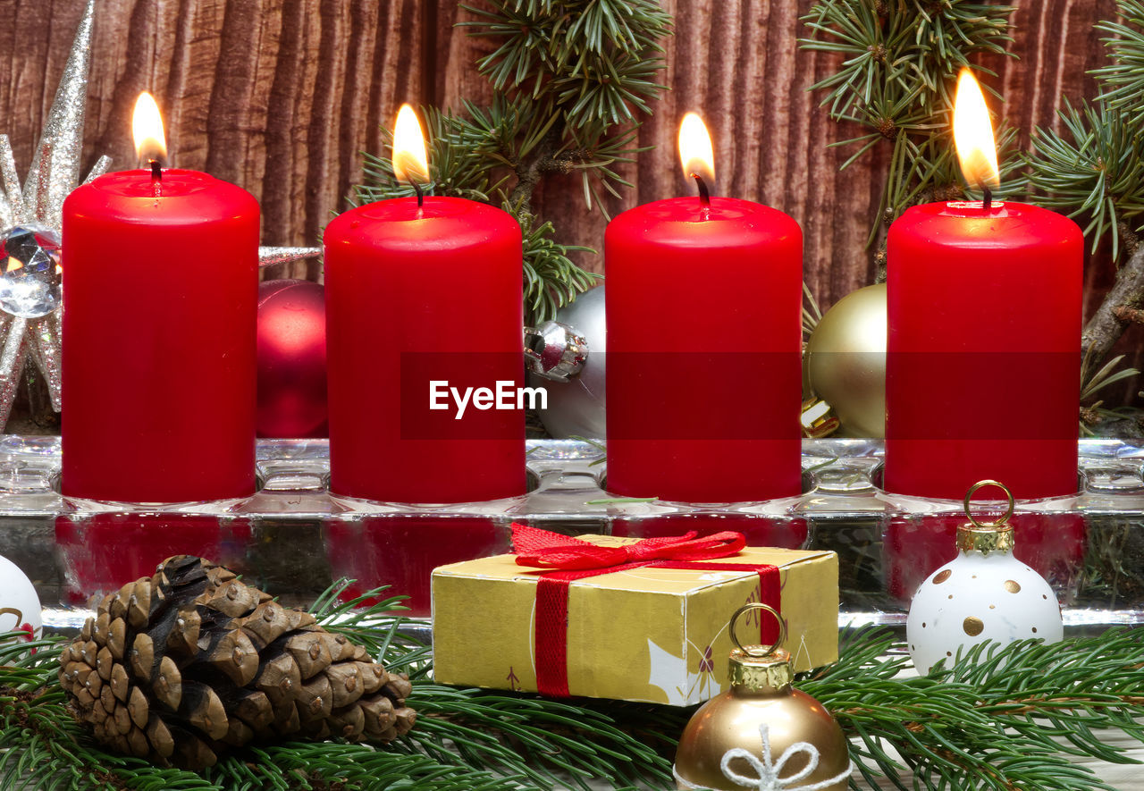 Red christmas candles and christmas gift boxes against wooden background
