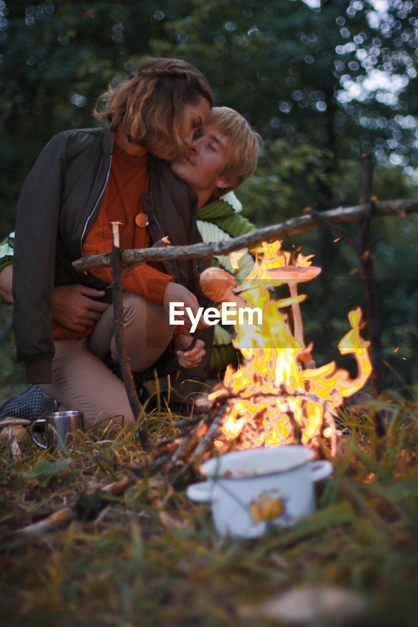 Romantic couple roasting mushrooms in forest