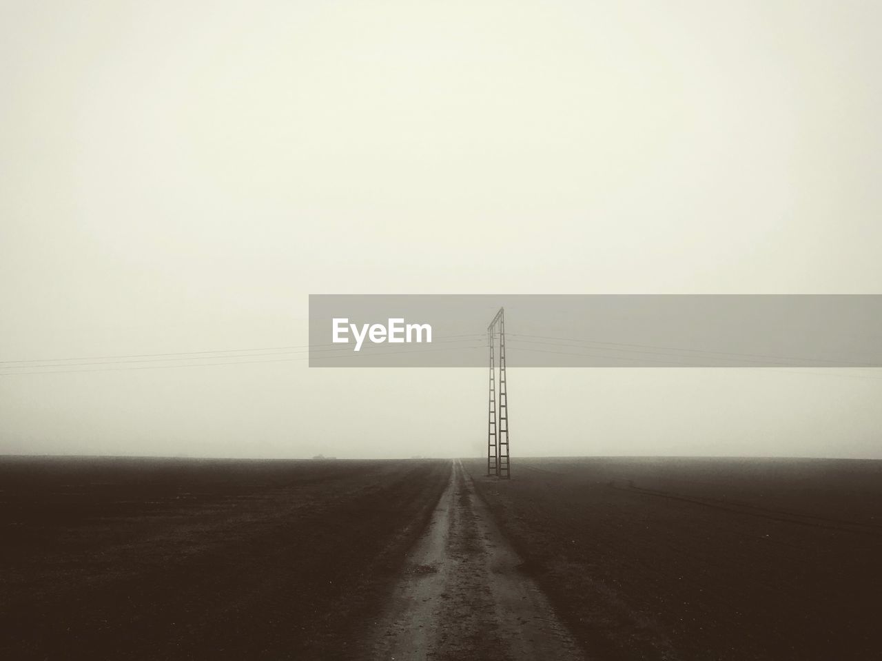 Electricity pylon on road against clear sky