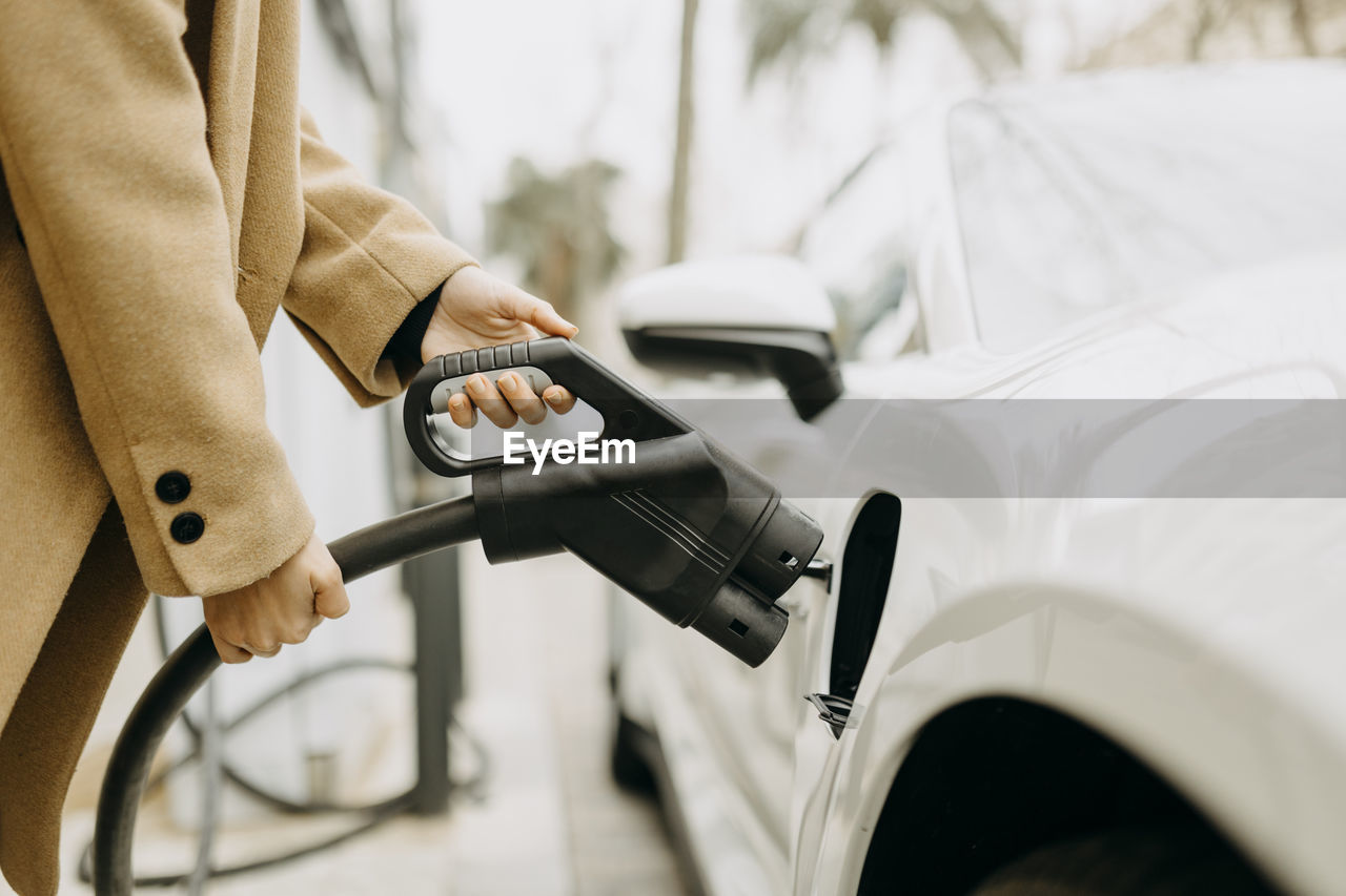 Woman charging electric car at station