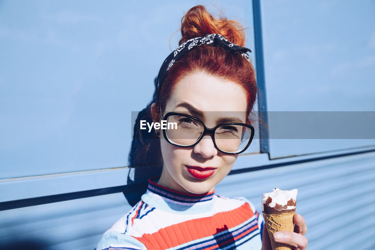 Portrait of redhead young woman holding ice cream cone against mini van