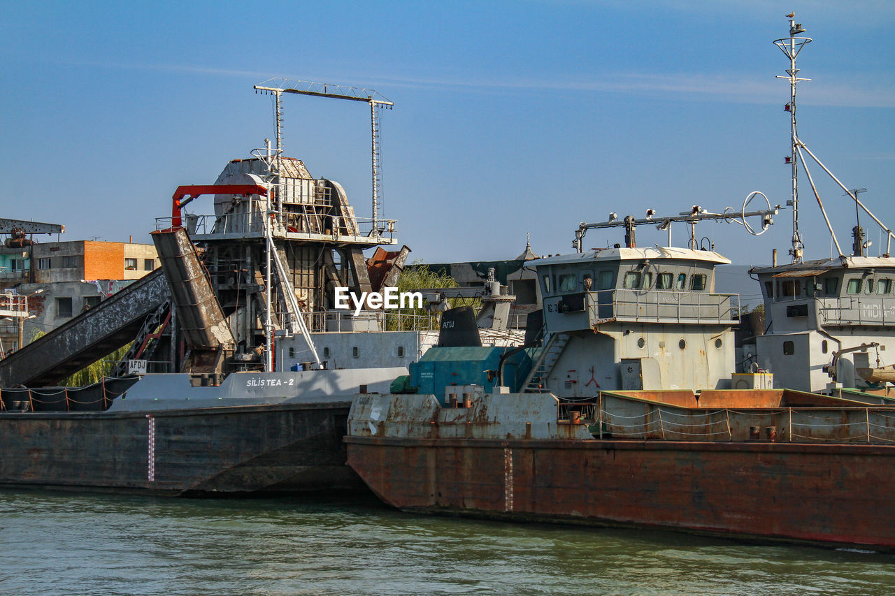 SHIP MOORED IN RIVER AGAINST CLEAR SKY