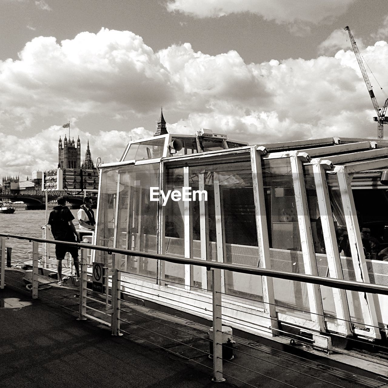 Ferry boat in river against cloudy sky