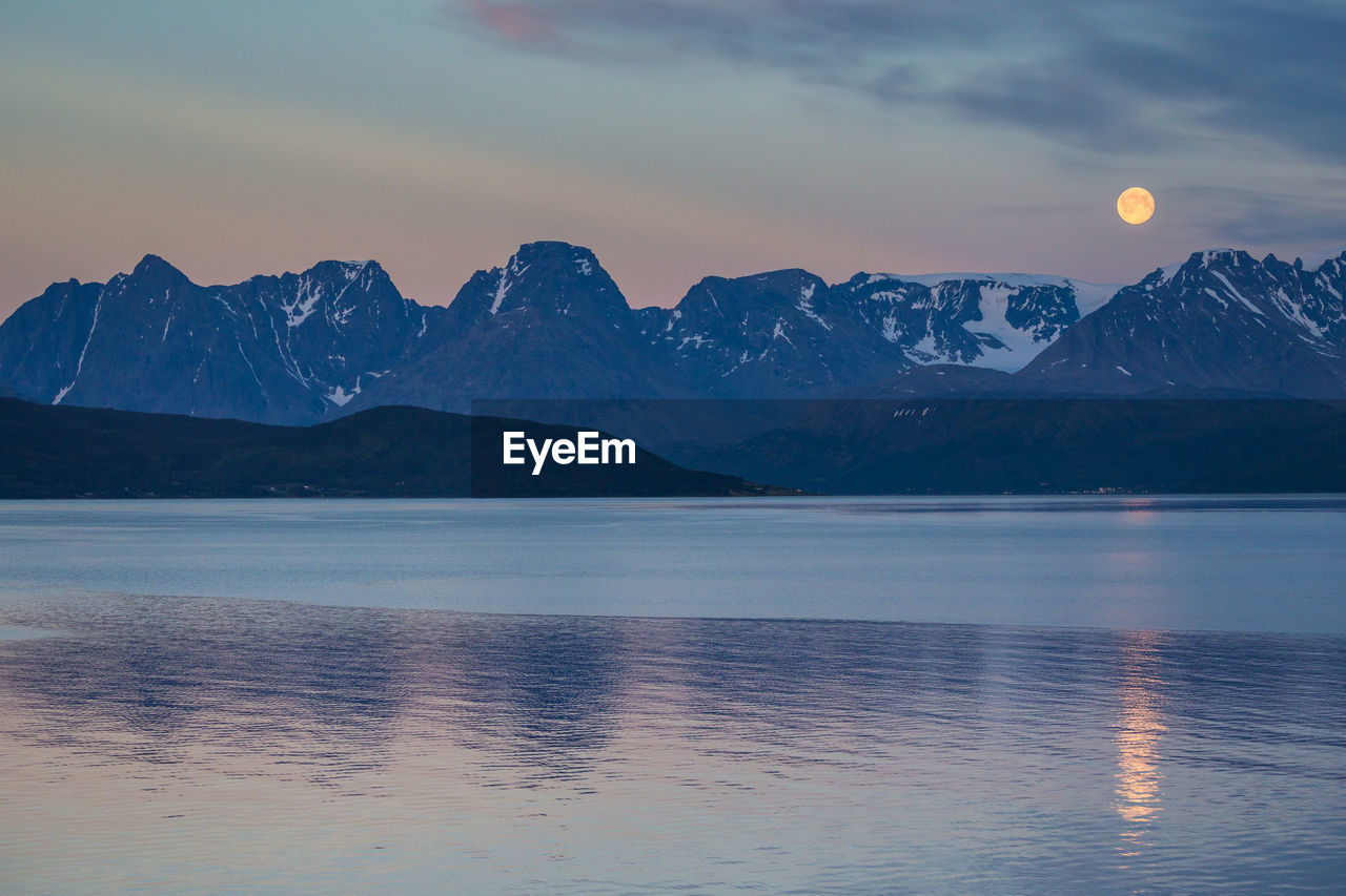 Scenic view of lake and mountain range against sky at dusk