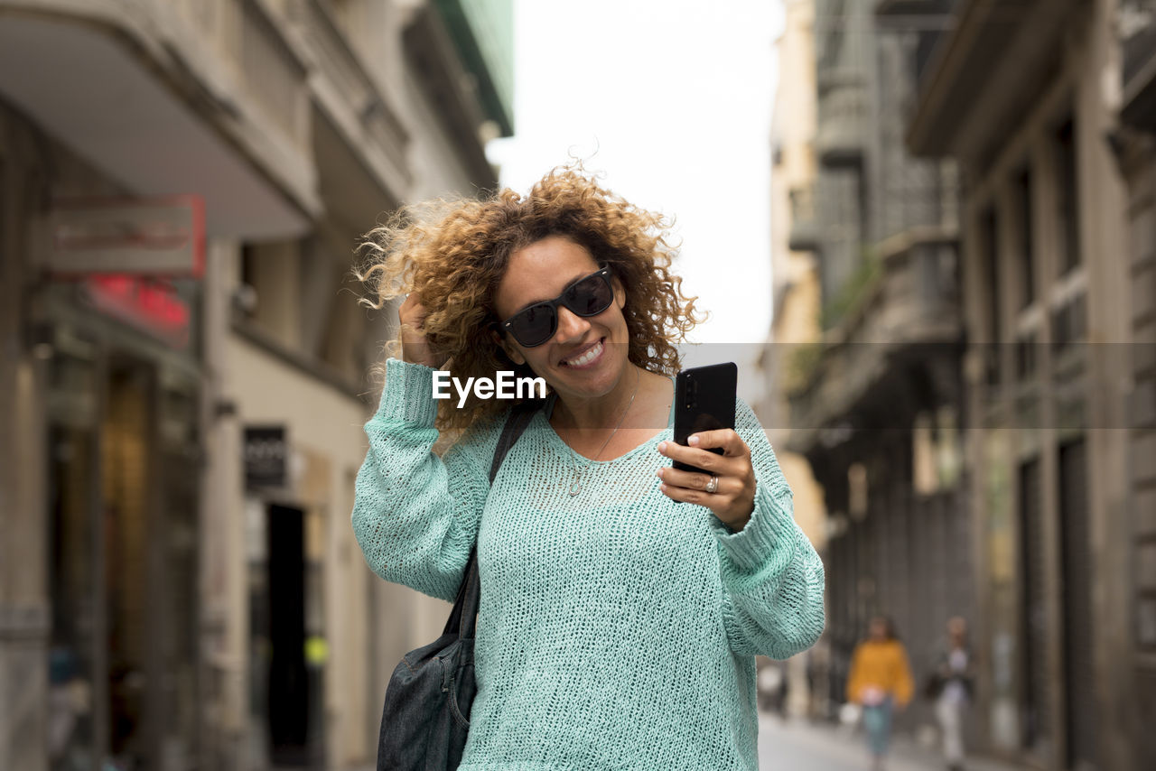 Portrait of smiling woman using phone in city