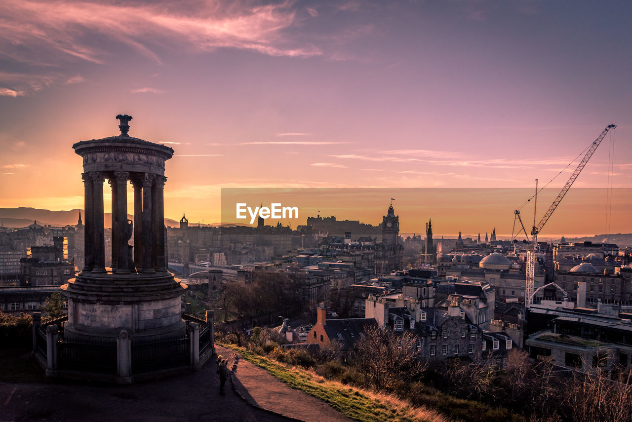 Sunset at dugald stewart monument with cityscape behind including edinburgh castle and north bridge