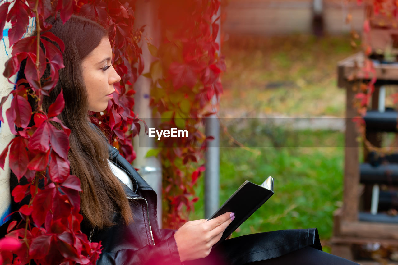 Woman reading book while sitting outdoors