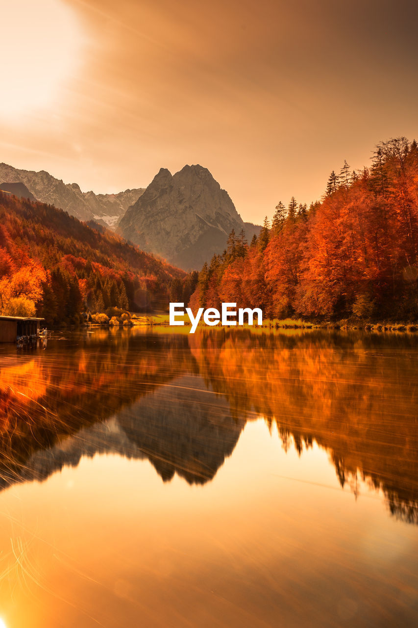 SCENIC VIEW OF LAKE BY MOUNTAINS AGAINST SKY DURING SUNSET