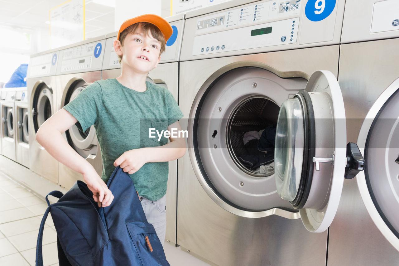 Boy using washing machine in room