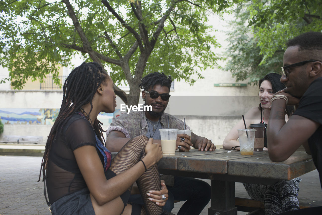 A group of friends having a conversation at a picnic table.