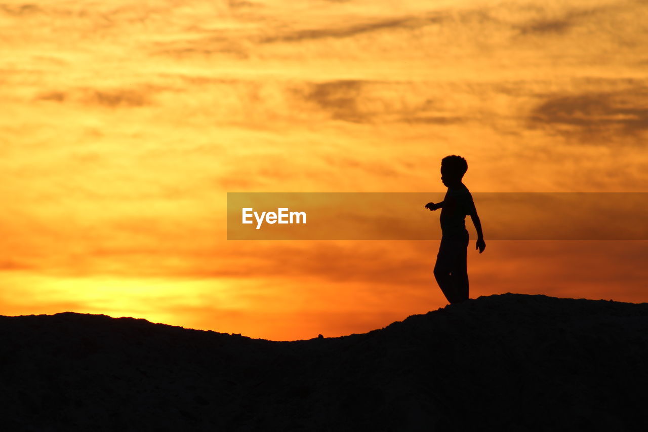 Silhouette person standing against sky during sunset