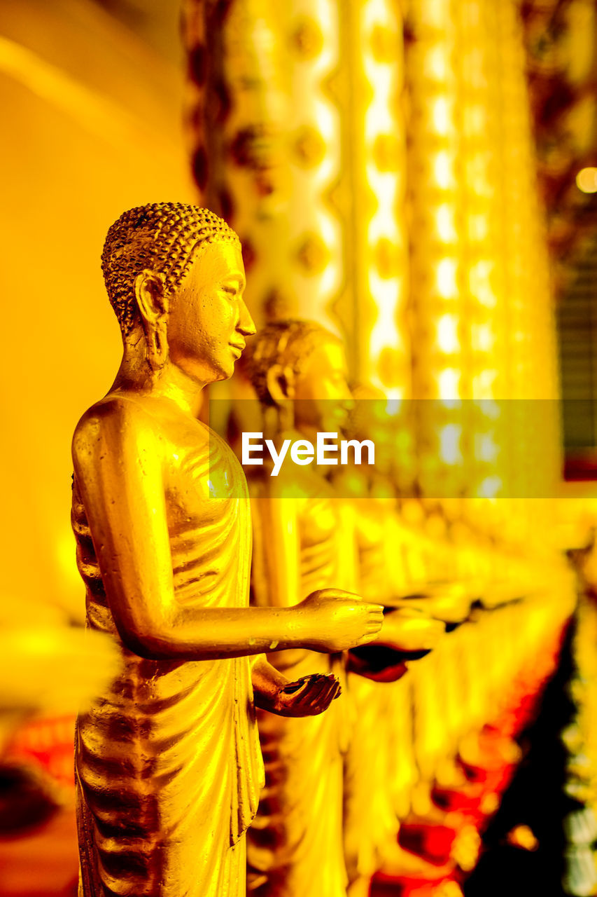 religion, belief, spirituality, yellow, sculpture, statue, gold, human representation, representation, temple, temple - building, male likeness, place of worship, no people, focus on foreground, architecture, building, indoors, built structure