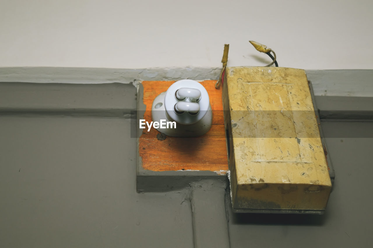 Low angle view of light bulb with door bell on gray wall