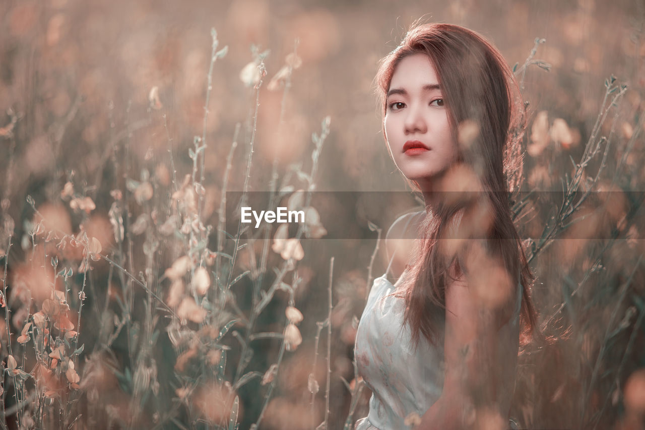 Portrait of young woman standing on field