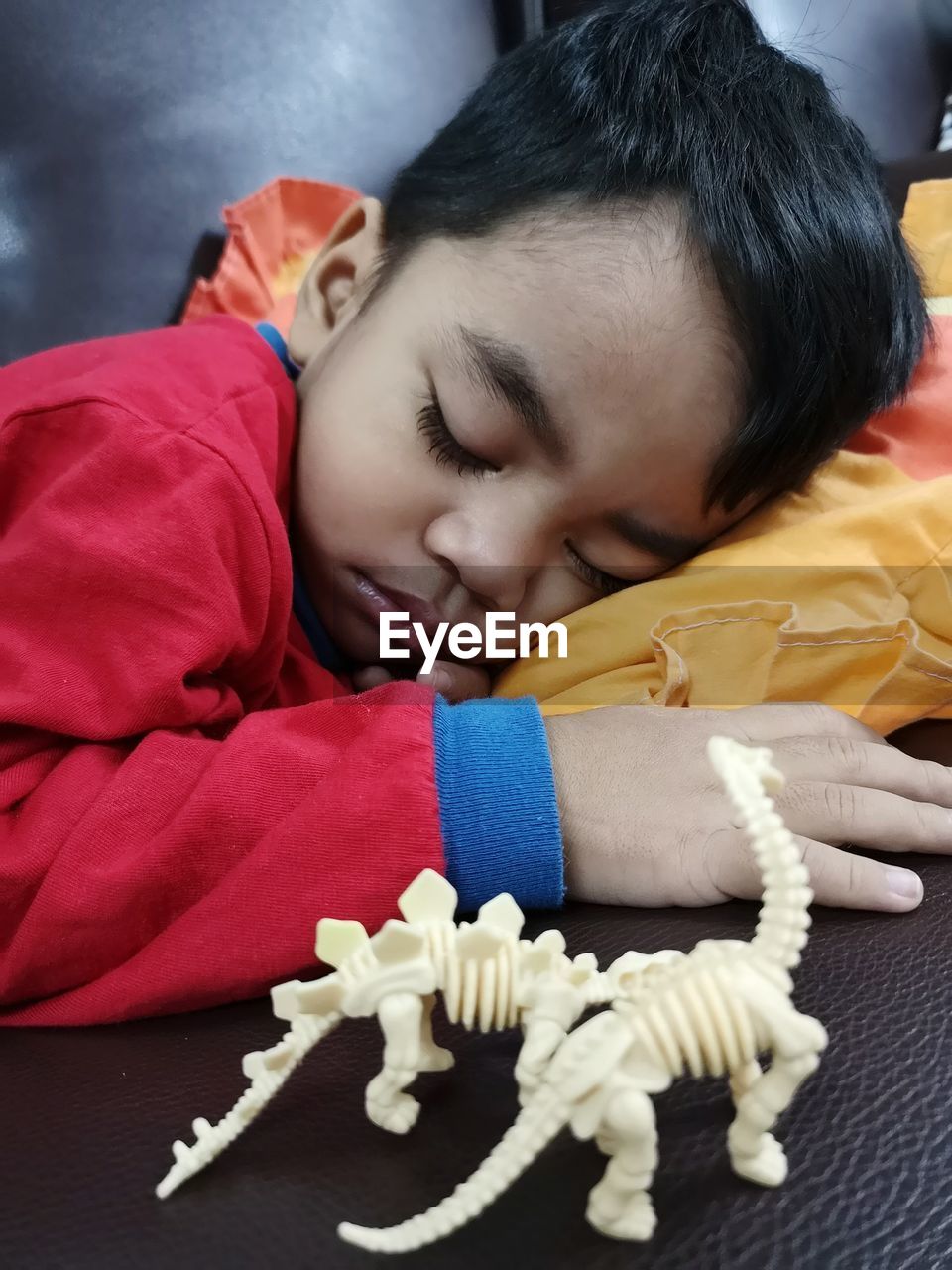 Cute boy sleeping by toys on sofa at home