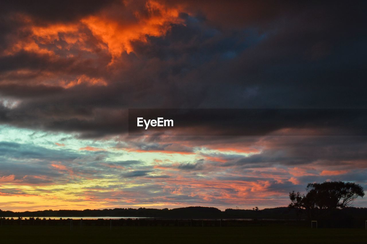 SILHOUETTE LANDSCAPE AGAINST DRAMATIC SKY DURING SUNSET