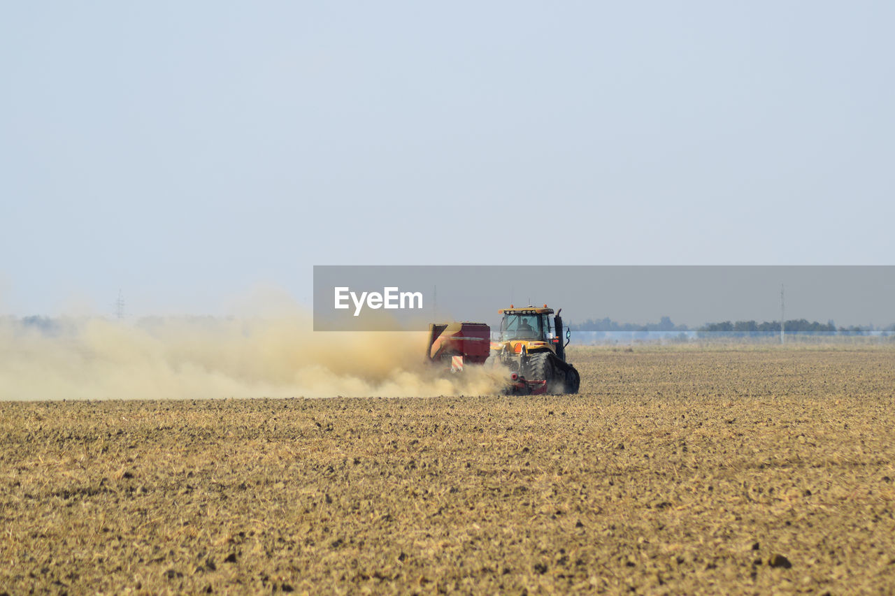 TRACTOR ON FIELD AGAINST CLEAR SKY