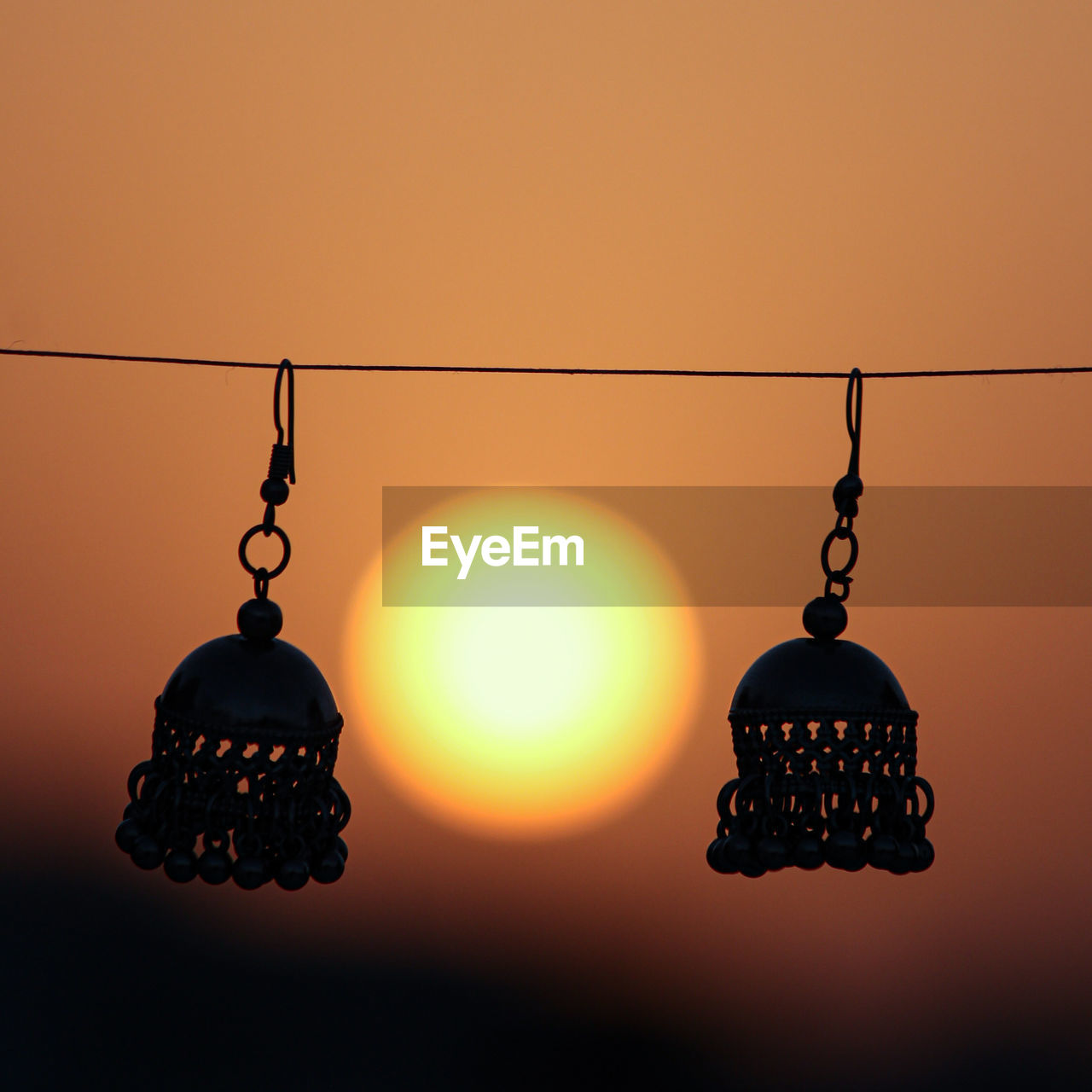 CLOSE-UP OF ILLUMINATED LAMP AGAINST ORANGE SKY