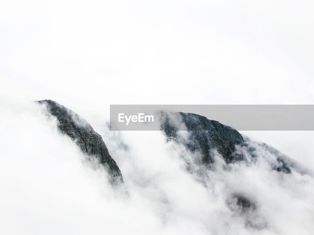 Scenic view of mountains amidst fog against sky