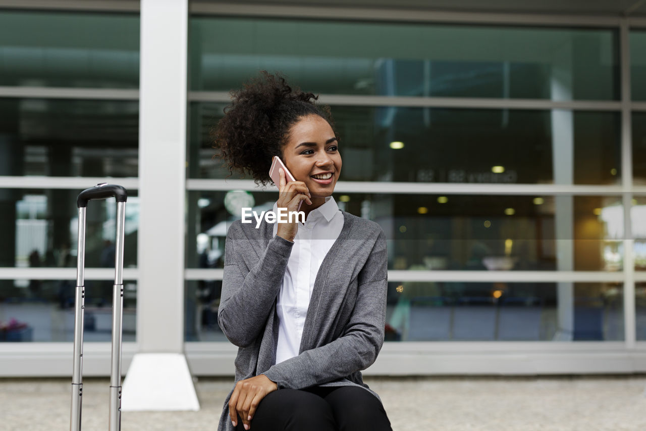 Close-up of businesswoman talking on phone while sitting outdoors