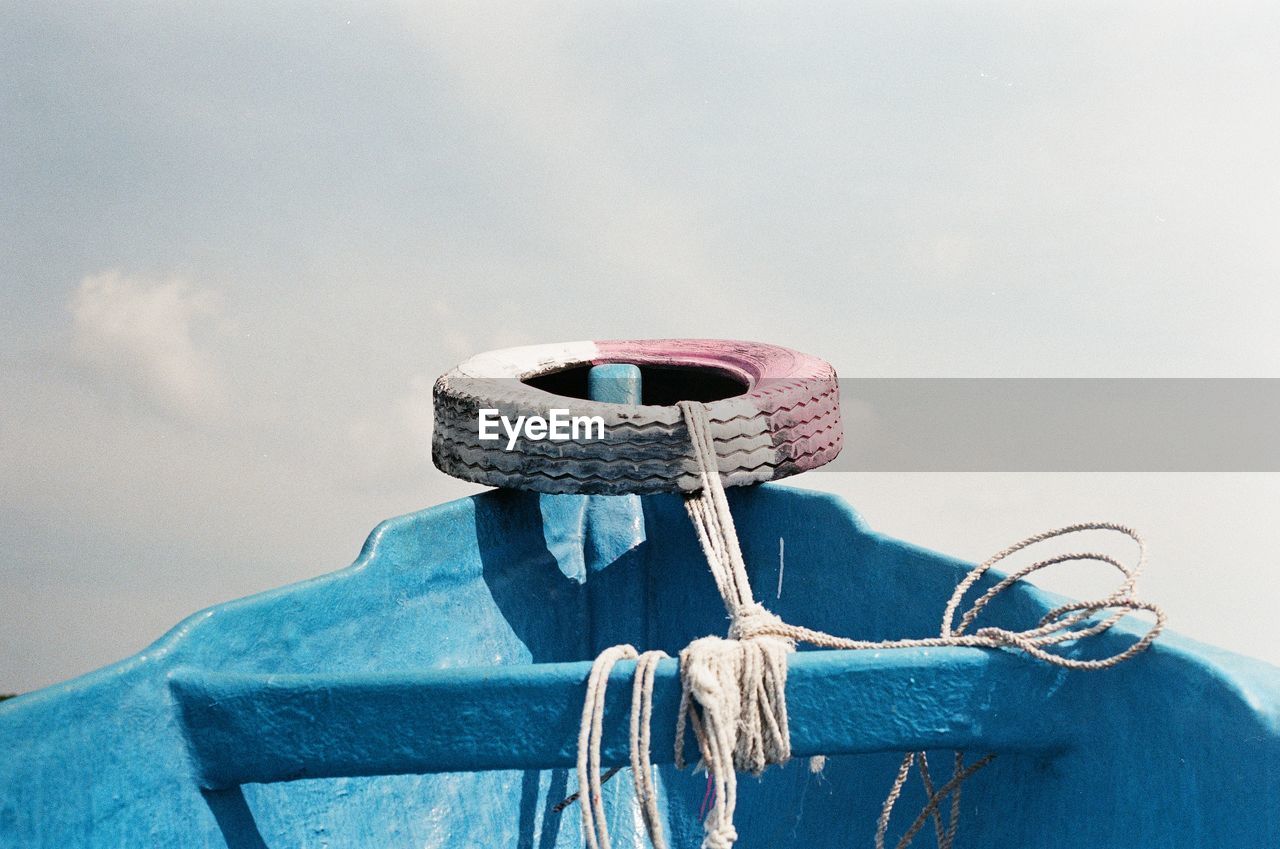 Close-up of rope tied to bollard against sky