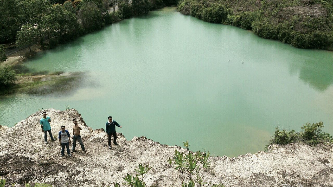 High angle view of men standing on cliff against lake