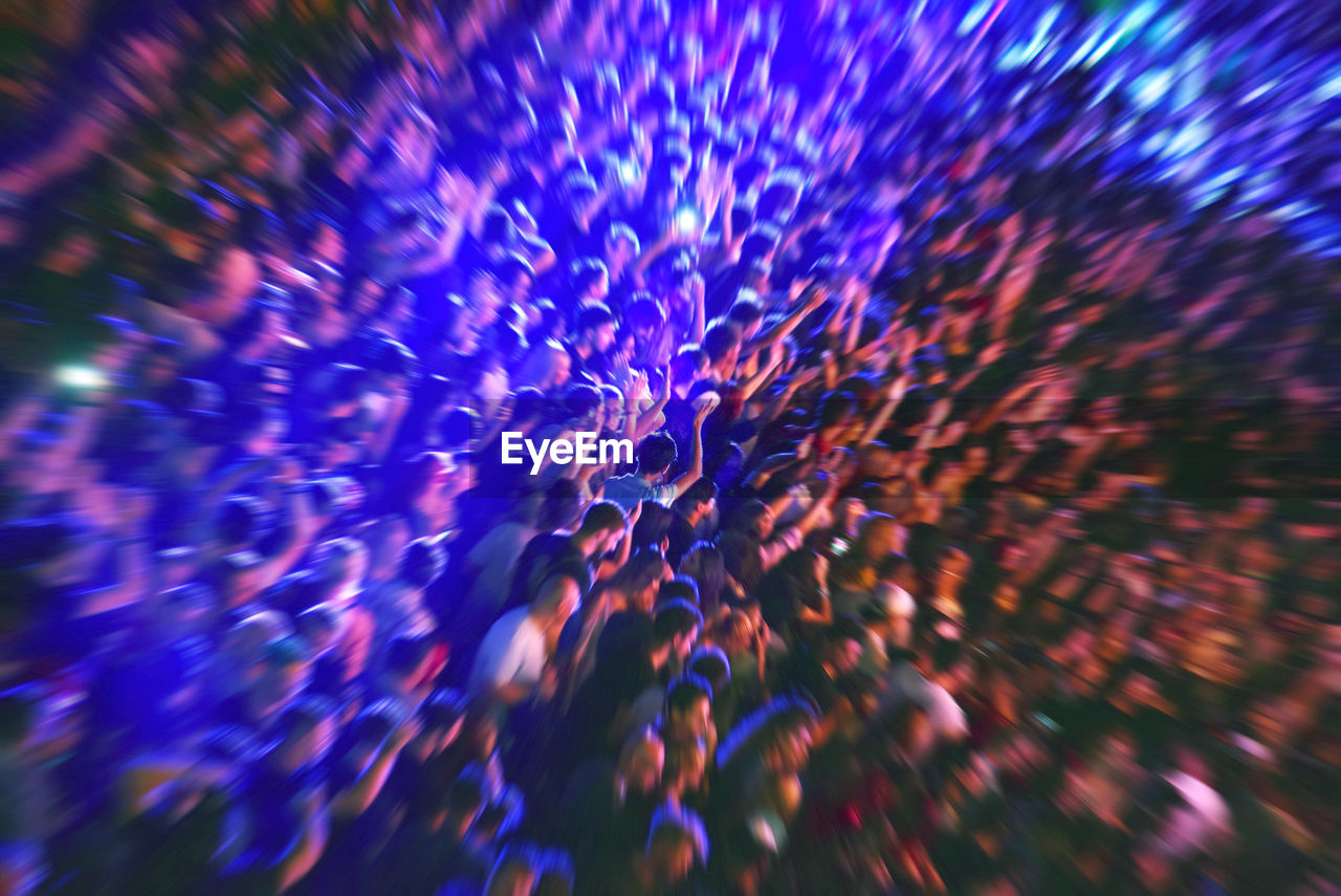 Zoom in effect on a blurred crowd partying at a music festival