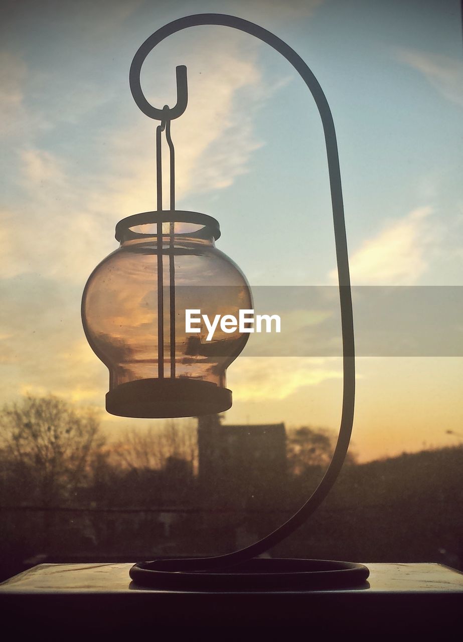 Close-up of vintage lantern against sky during sunset