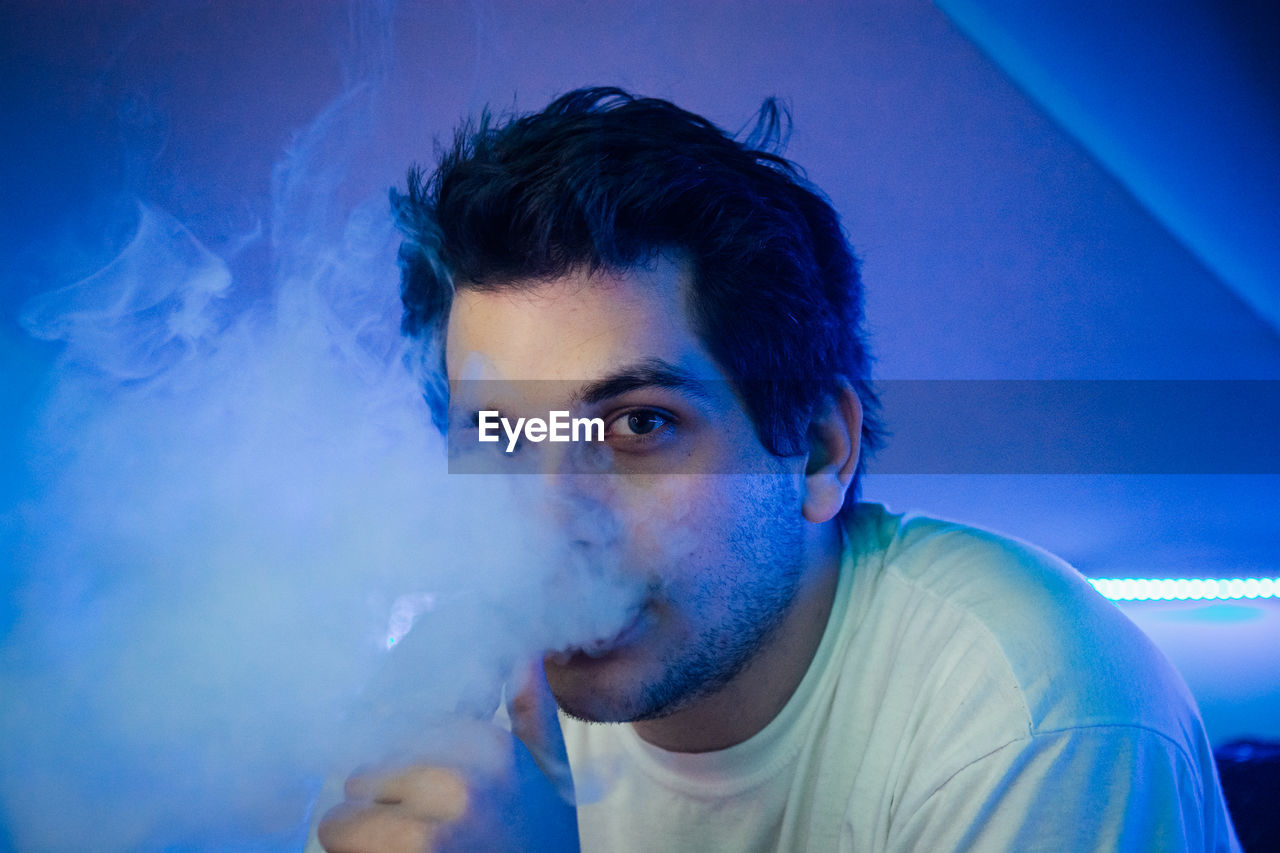 Close-up portrait of young man smoking in club