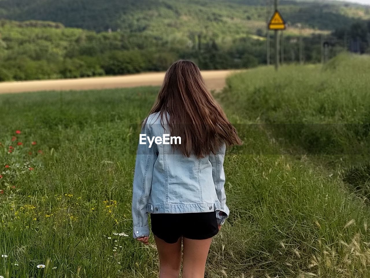 Rear view of girl standing on grassy field