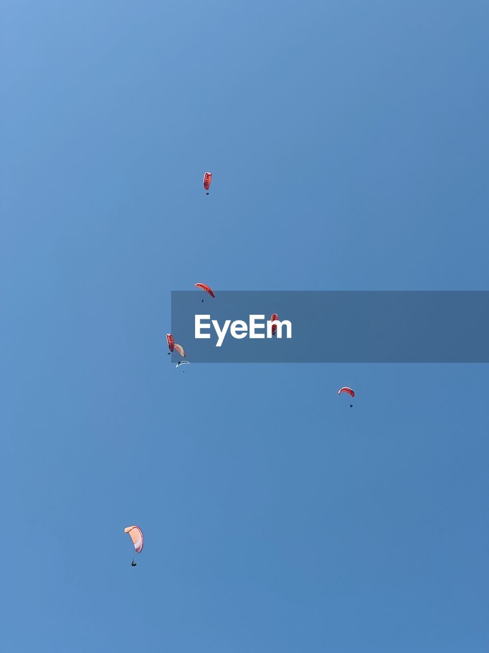flying, sky, blue, mid-air, clear sky, adventure, nature, low angle view, transportation, balloon, air vehicle, parachute, day, hot air balloon, sunny, extreme sports, no people, sports, multi colored, toy, leisure activity, environment, motion, outdoors, windsports, air sports, wind, copy space