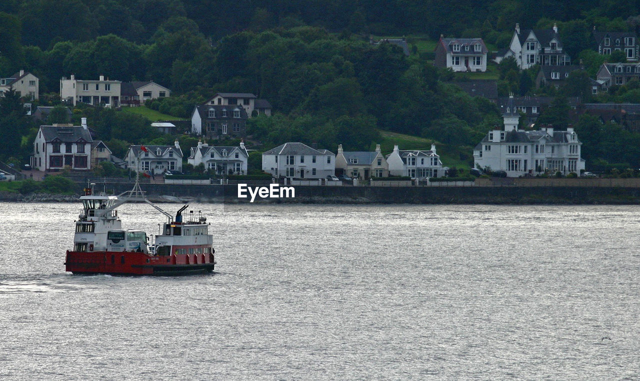 BOAT SAILING ON RIVER IN CITY