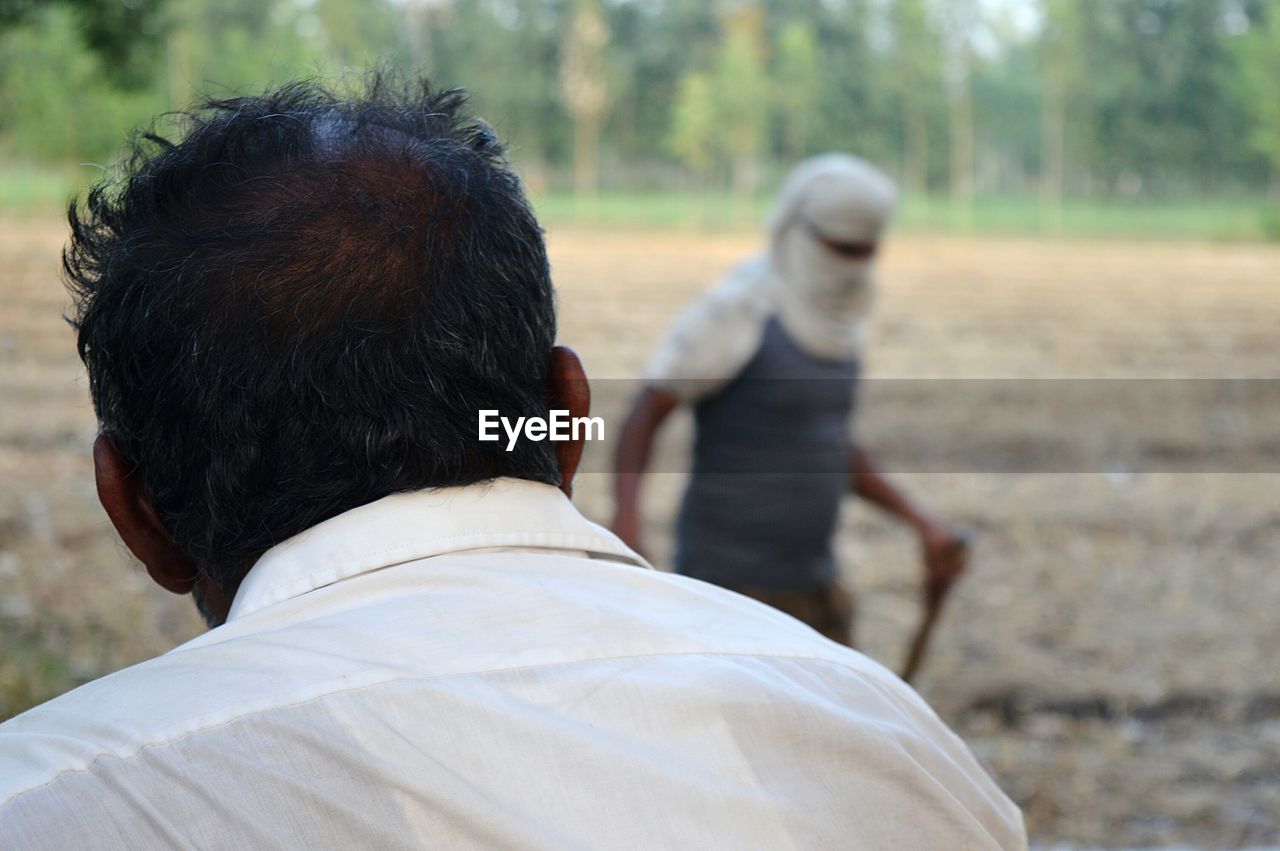 Rear view of mid adult man standing at farm