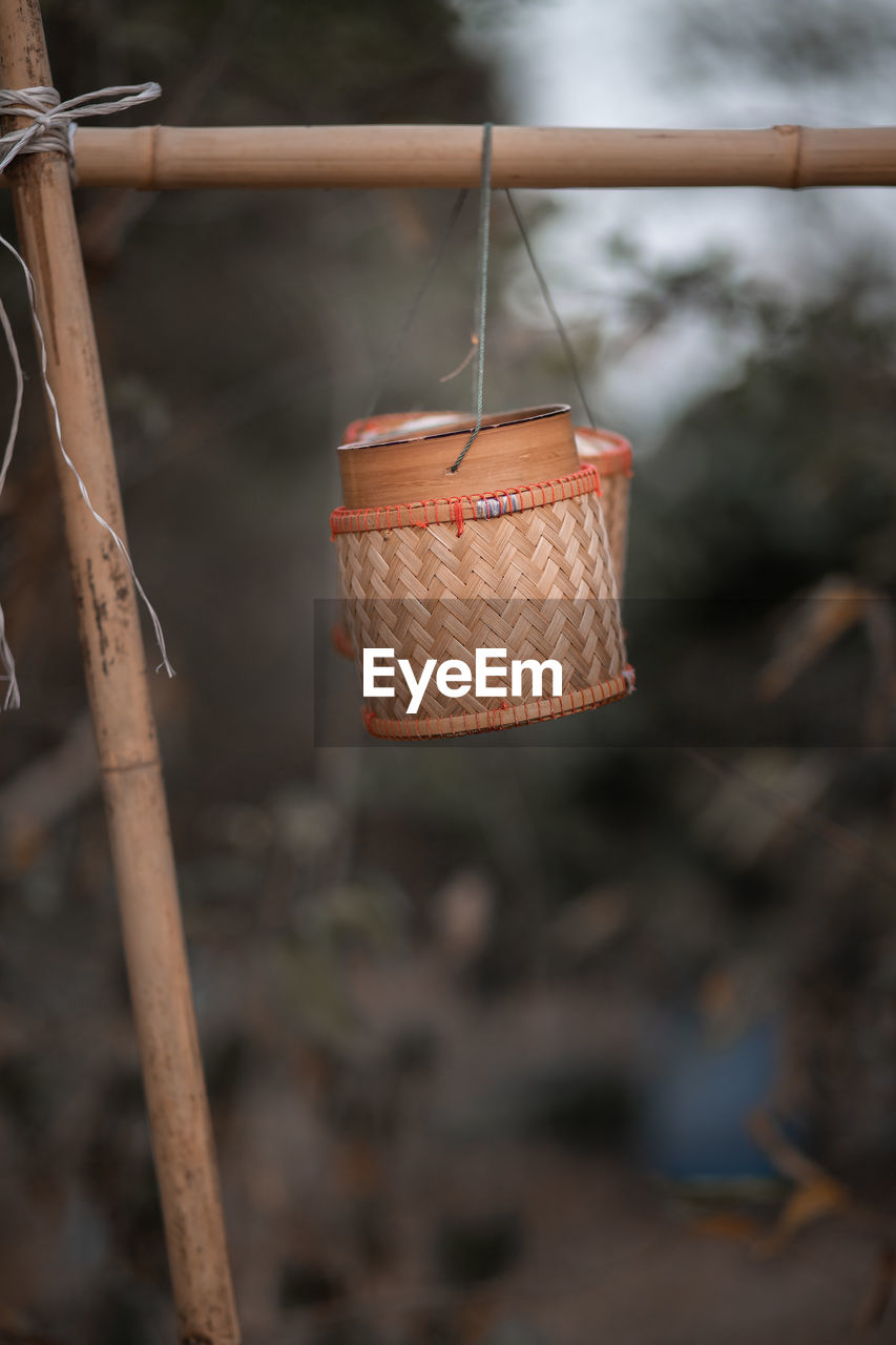 Close-up of wicker basket hanging on wood outdoors