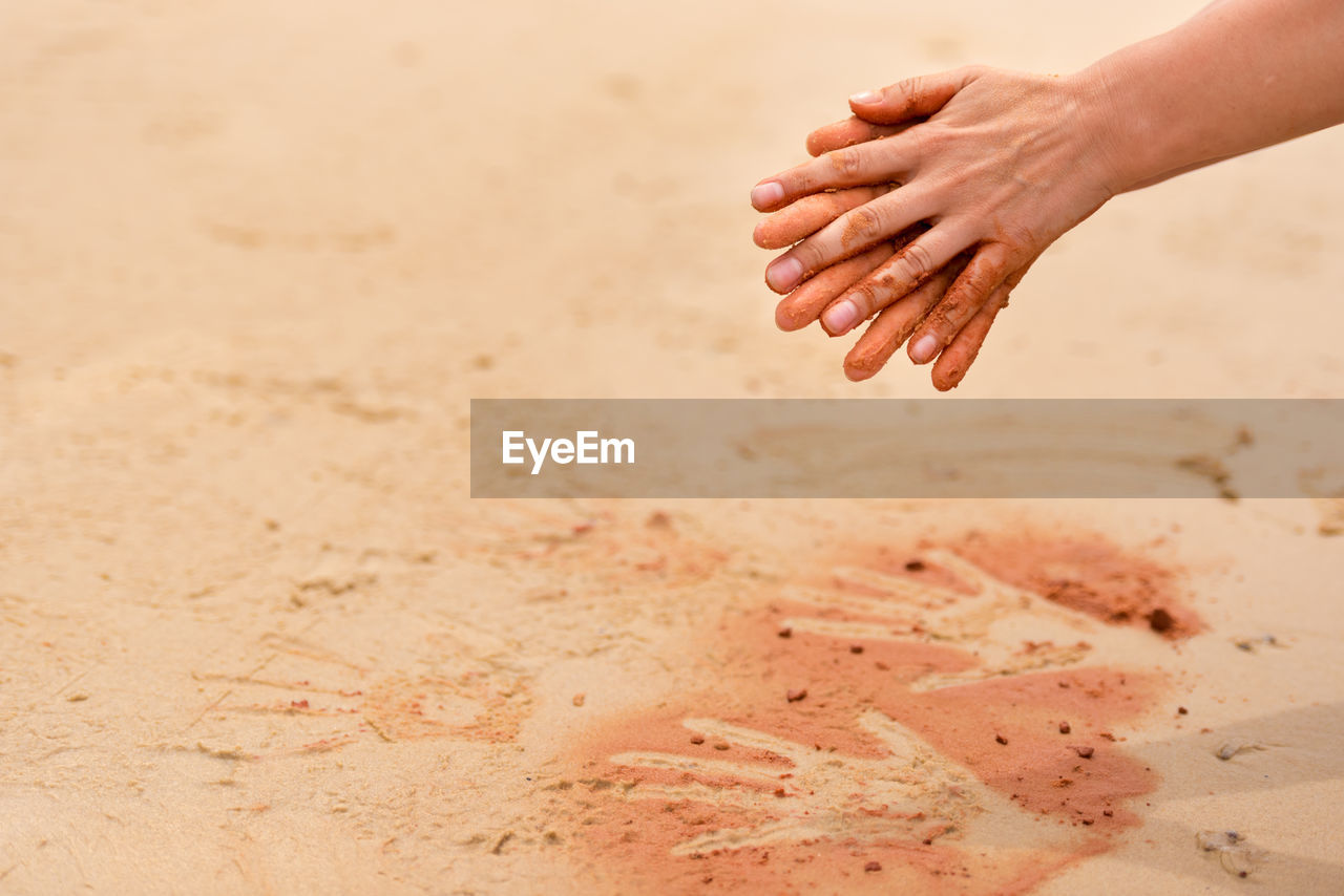 Cropped hands over sand at beach