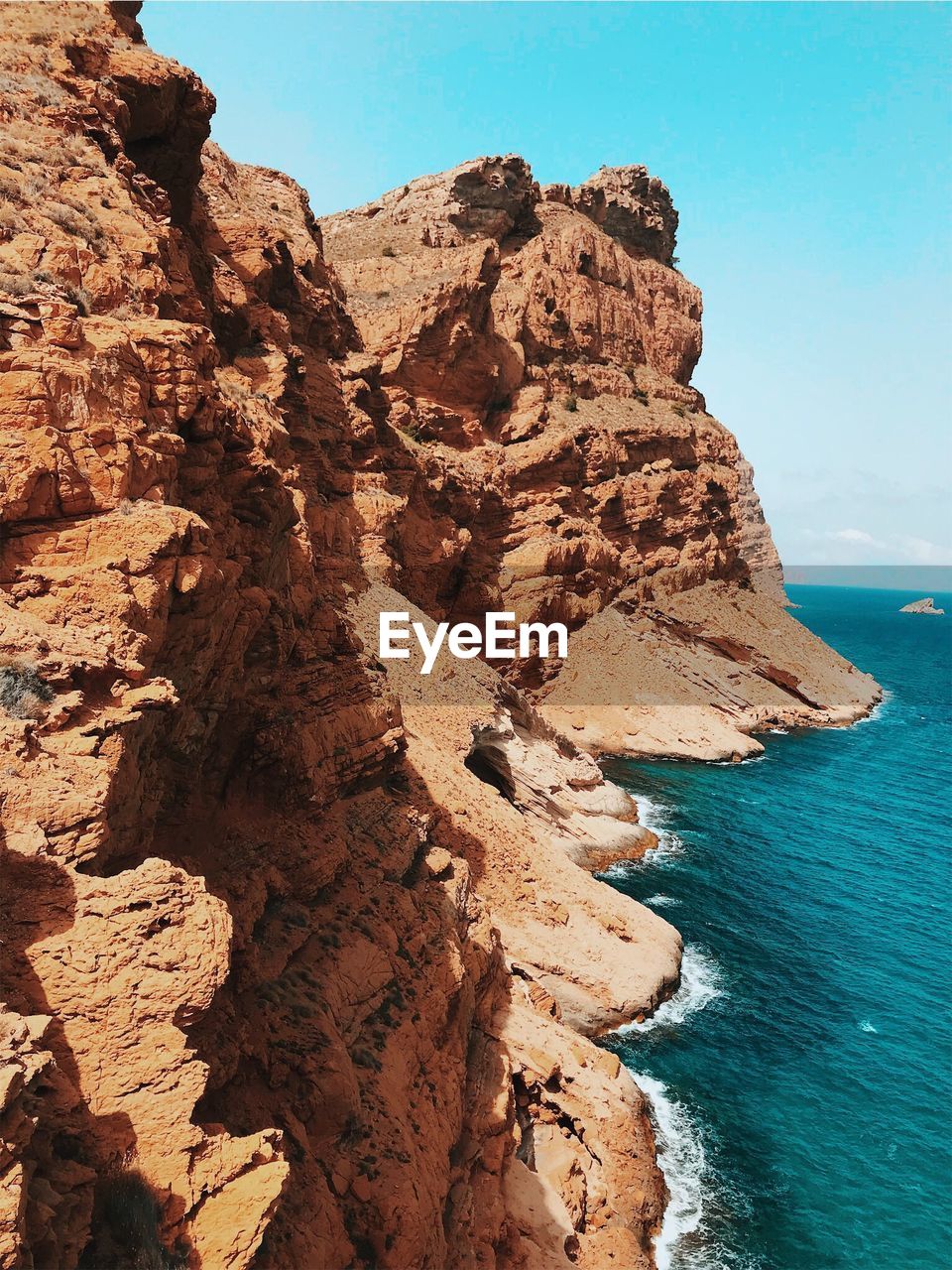 Rock formation on beach against clear blue sky