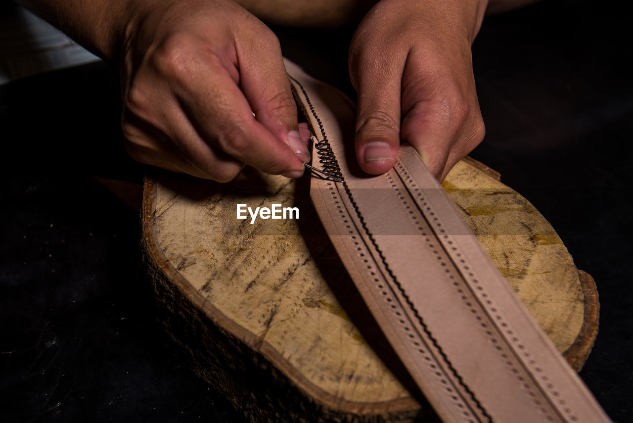Close-up of craftsperson making belt in workshop