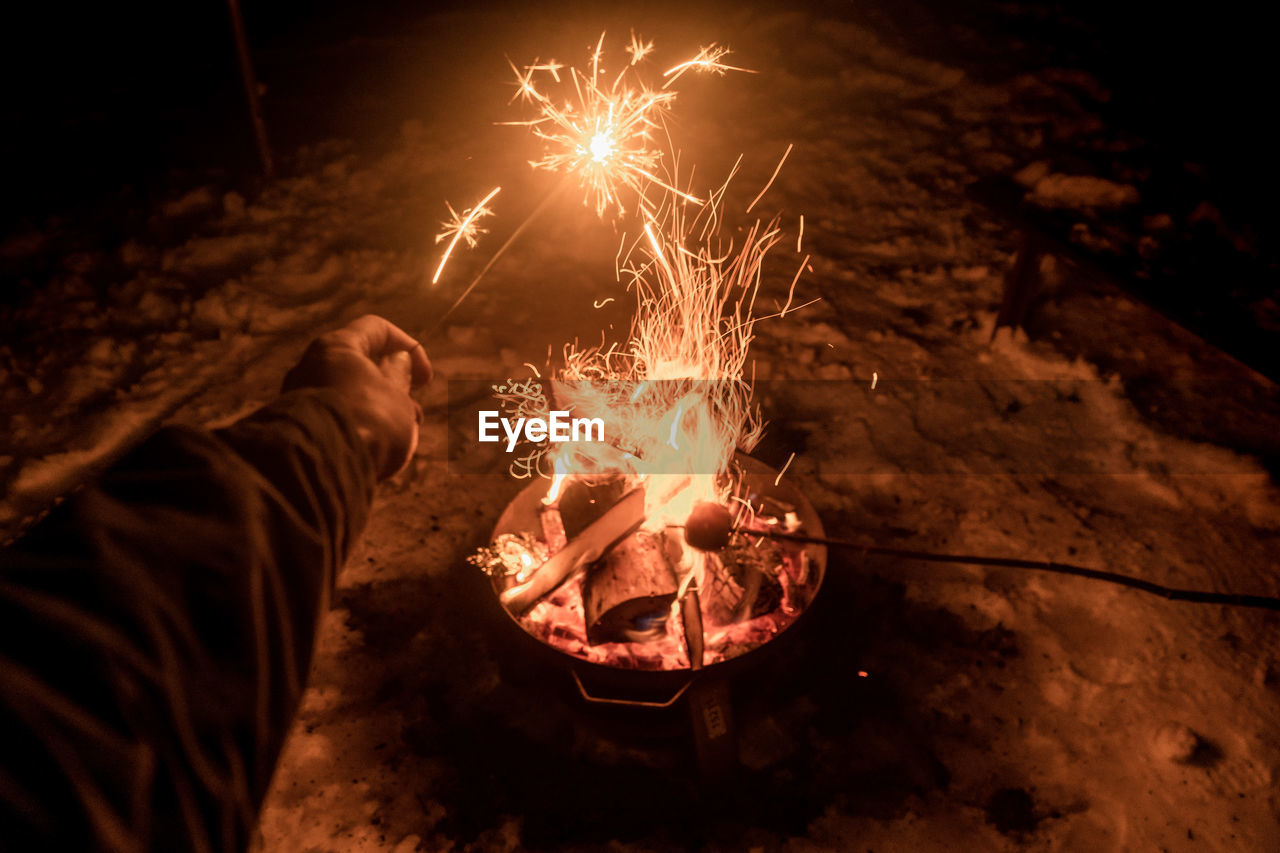 Midsection of man with fire crackers at night