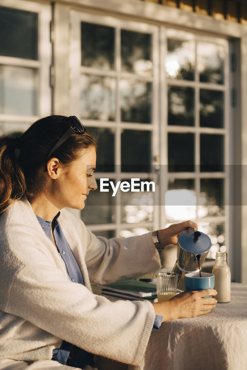 Mature woman pouring coffee at table in holiday villa