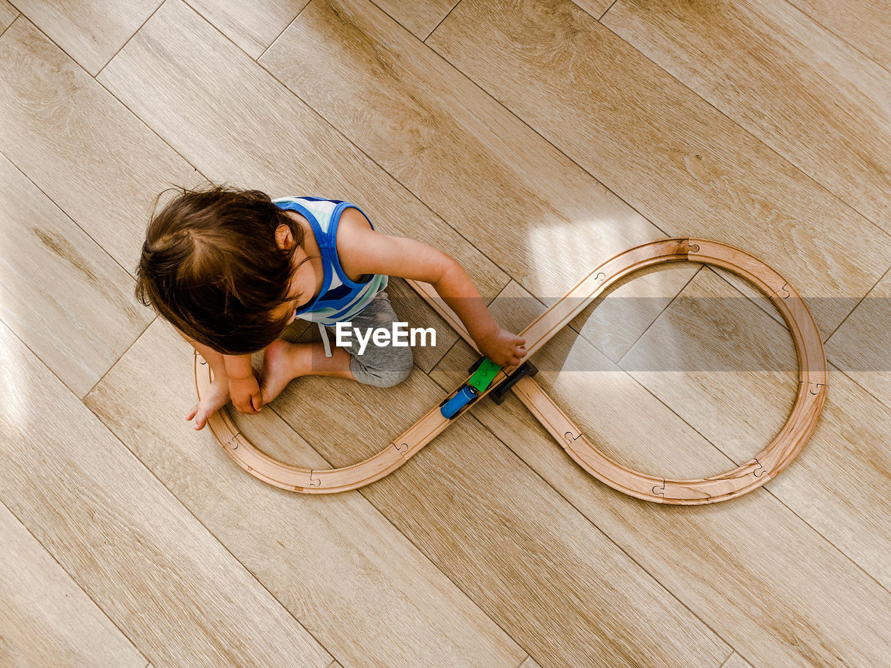A toddler playing with toy trains sitting on the floor
