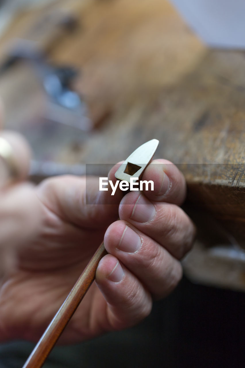 Cropped hands of woman repairing violin string