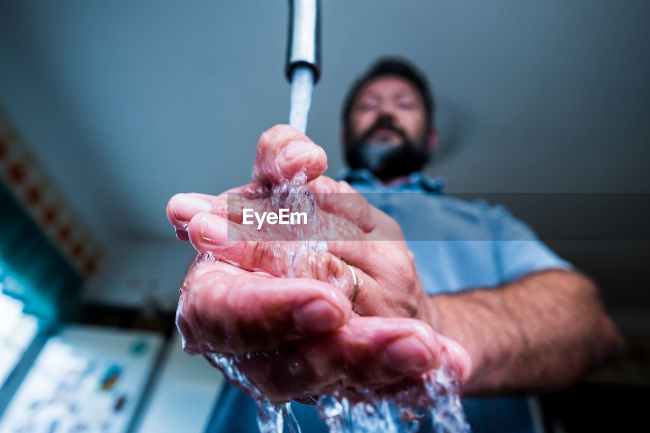 Low angle view of man washing hands at home