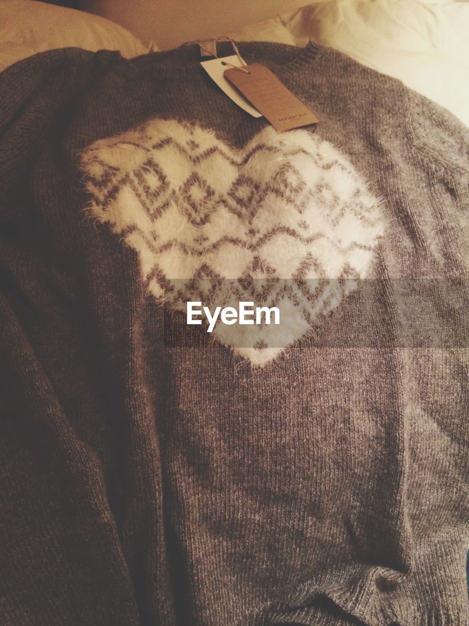 High angle view of new sweater with price tag on bed