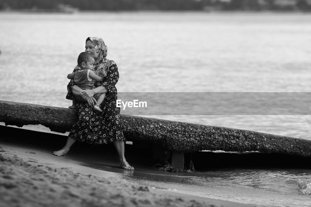 Woman sitting with son on seat at beach