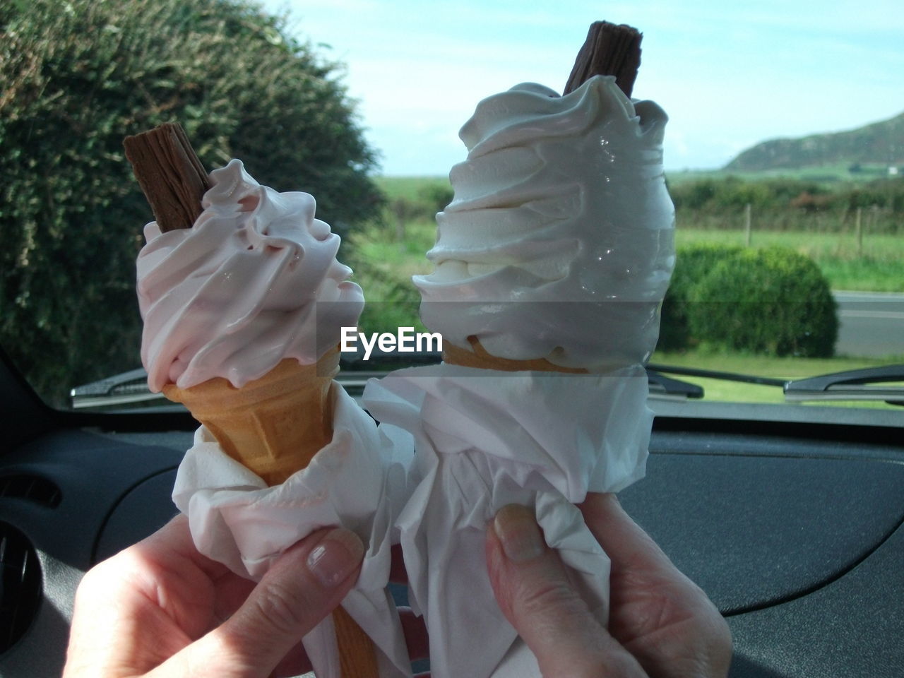 Cropped hands holding ice cream in car