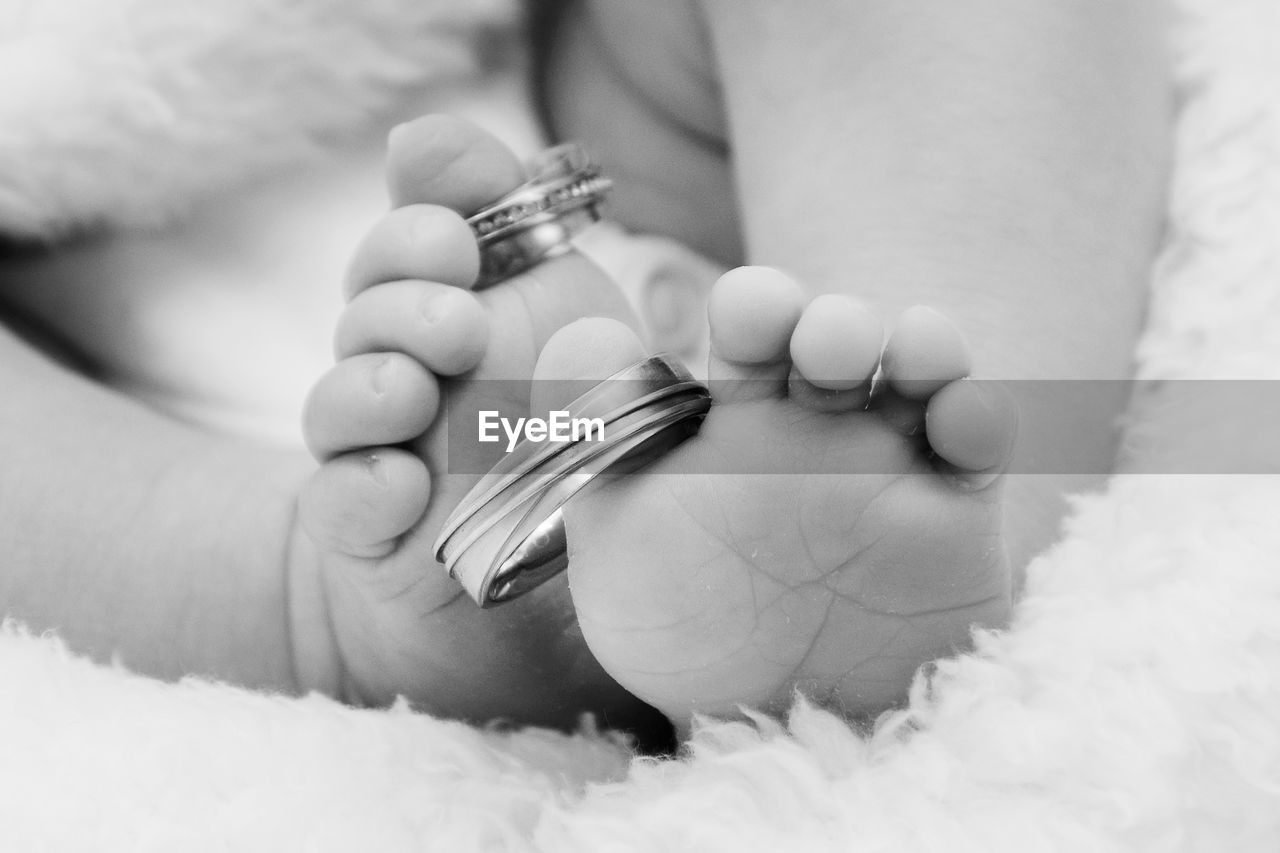 Low section of baby with wedding rings on toes