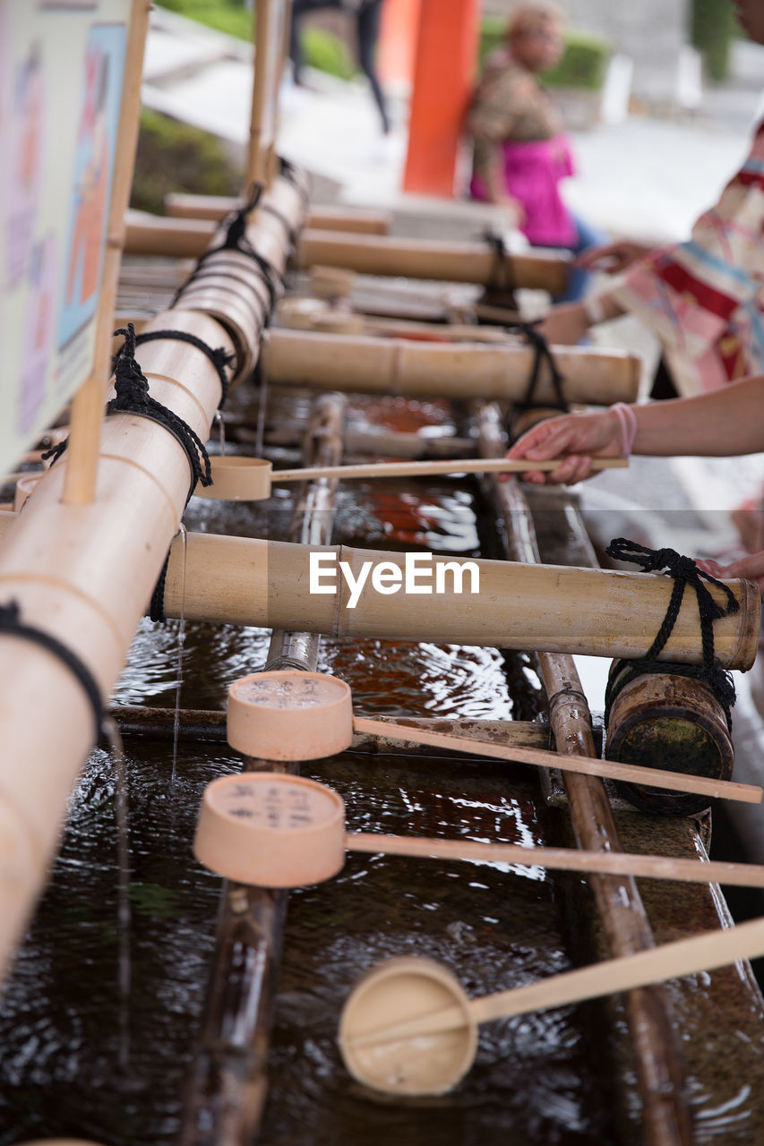 Close-up of cropped hand holding container by drinking water in temple