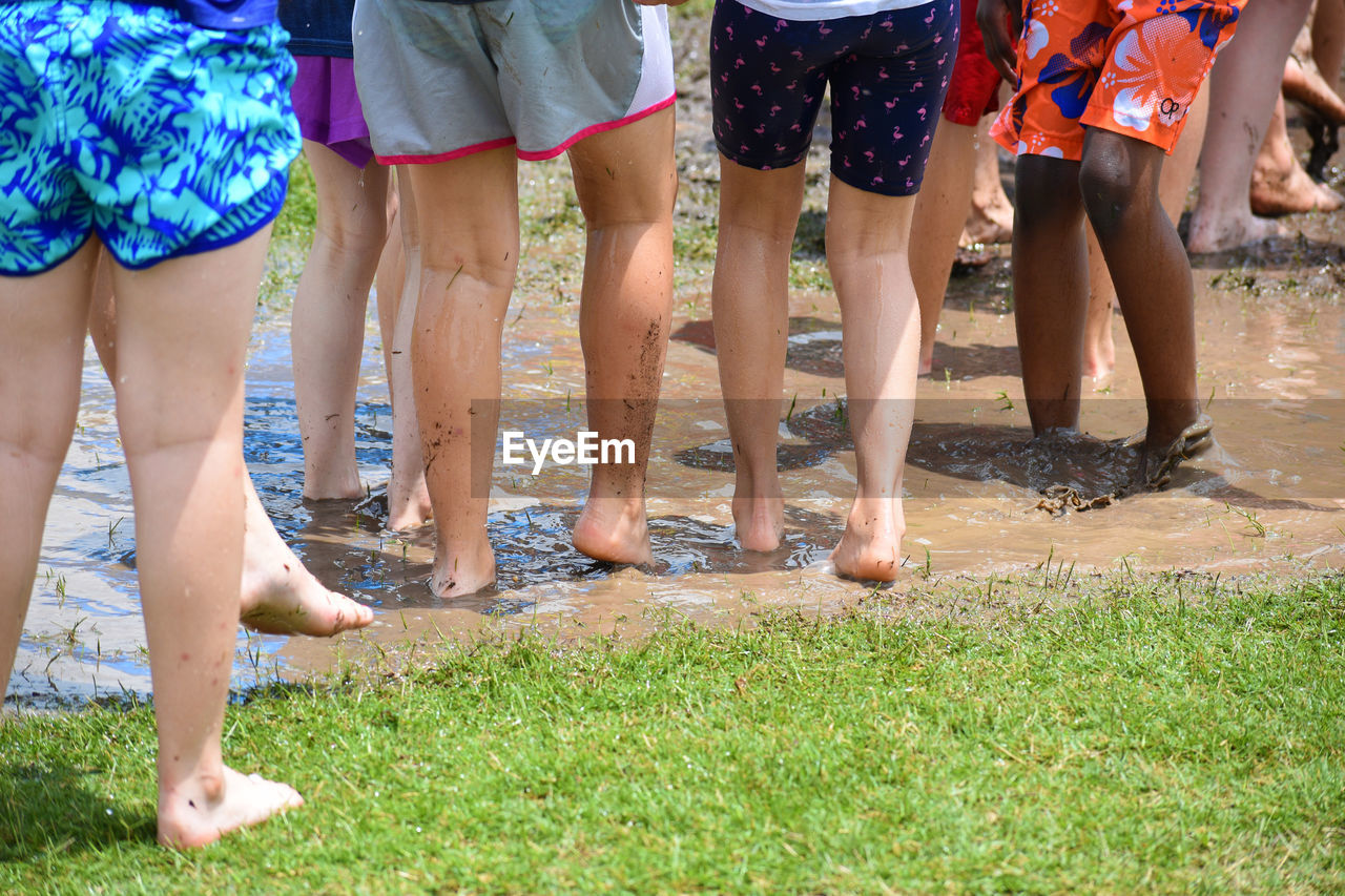 Low section of children standing in muddy puddle