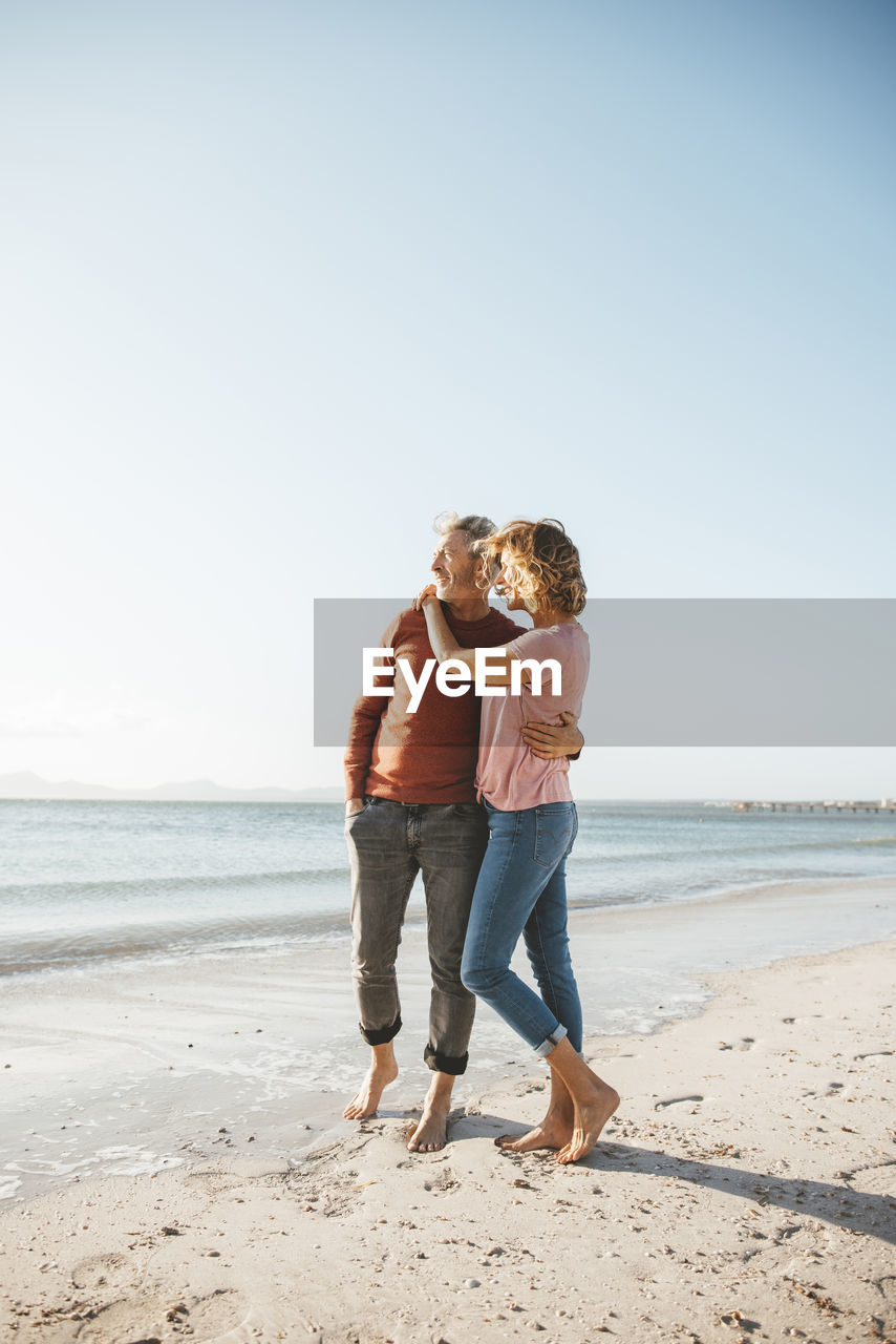 Mature couple standing on shore at beach