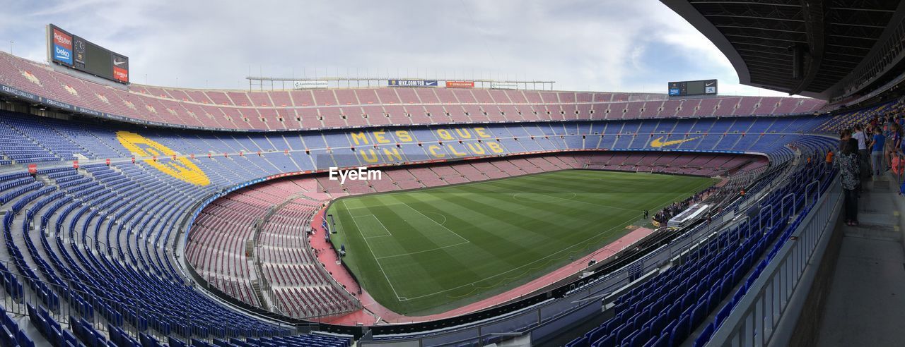 HIGH ANGLE VIEW OF EMPTY STADIUM AGAINST CLOUDY SKY